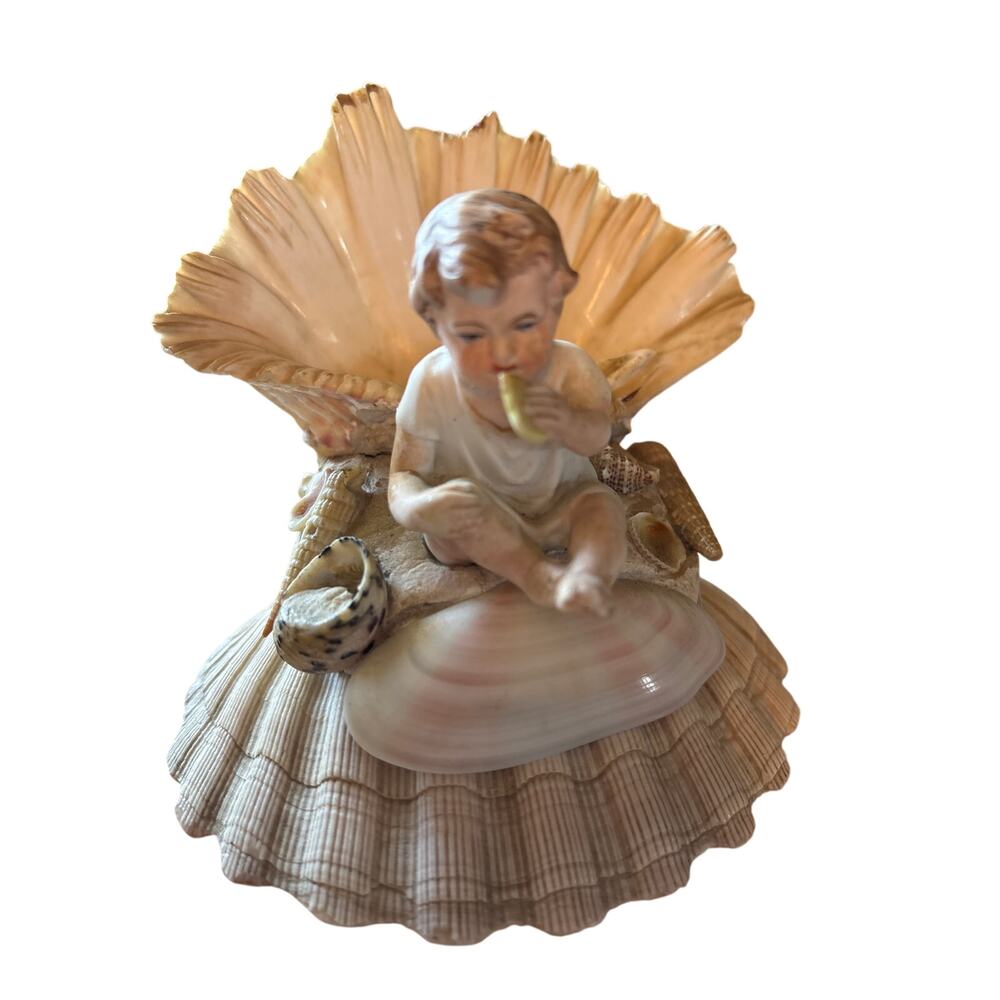 vintage bisque or porcelain figurine features a cherub pn shells